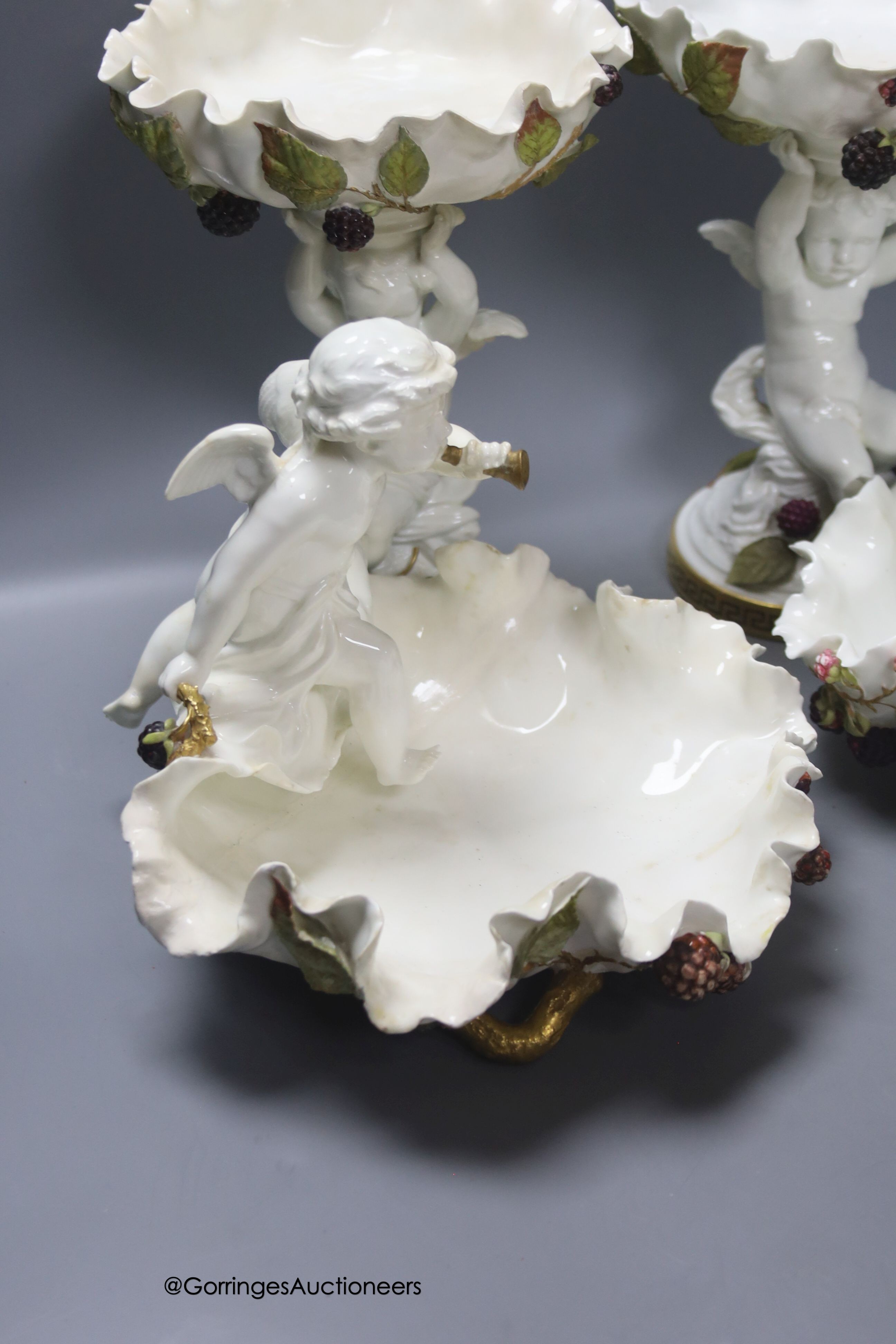 A pair of Moore Bros leaf pattern bowls, encrusted with fruit and surmounted by cherubs and a similar pair of tazza stands, height 24cm